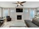 Comfortable living room with a fireplace, mounted TV, large windows and light-colored wood look flooring at 6609 Truxton Ln, Raleigh, NC 27616