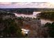 Stunning aerial view of modern home surrounded by forest and lake at sunset at 721 Jones Ferry Rd, Chapel Hill, NC 27516