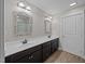 Bathroom featuring double sinks, decorative mirrors, dark cabinets, and modern lighting fixtures at 818 Houston Ct, Haw River, NC 27258