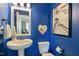 Stylish powder room with bold blue walls, a pedestal sink, and unique decor at 1025 Chelsea Run Ln, Apex, NC 27502