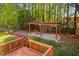 Backyard with a hammock under a pergola on a stone base surrounded by green grass, natural mulch, and trees at 1100 Dotson Way, Apex, NC 27523