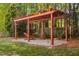 Backyard view of a hammock under a pergola on a stone base surrounded by green grass and trees at 1100 Dotson Way, Apex, NC 27523