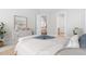 This staged bedroom features a large bed, storage cabinet, beach-themed art, and neutral walls at 1100 Dotson Way, Apex, NC 27523