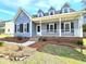 Inviting front porch with white railing, complemented by neat landscaping and brick accents at 117 Woodcroft Drive Dr, Angier, NC 27501