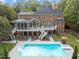 Stunning backyard with a large pool, manicured lawn, brick house, and multiple decks at 12012 Six Forks Rd, Raleigh, NC 27614