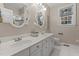 Bright bathroom with a double vanity, decorative mirrors, and white tiled flooring and includes a shower behind glass door at 12012 Six Forks Rd, Raleigh, NC 27614