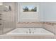 Bright bathroom featuring a built-in soaking tub with tiled backsplash and a separate shower at 12012 Six Forks Rd, Raleigh, NC 27614