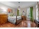 Cozy bedroom featuring hardwood floors, a wood-framed bed, and bright windows with decorative green curtains at 12012 Six Forks Rd, Raleigh, NC 27614
