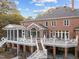 Expansive brick home with a large deck and outdoor living spaces with stairs to the ground level at 12012 Six Forks Rd, Raleigh, NC 27614