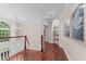 Elegant hallway with hardwood floors, arched doorways, built-in shelving, and a chandelier, adjacent to a staircase at 12012 Six Forks Rd, Raleigh, NC 27614
