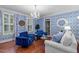 Cozy living room showcasing blue and white wallpaper, a chandelier, plantation shutters, and rich wood floors at 12012 Six Forks Rd, Raleigh, NC 27614