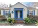 Charming home featuring a symmetrical facade with blue trim and shutters, complemented by lush, mature landscaping at 1301 Clarendon St, Durham, NC 27705