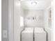 Clean laundry room with stacked washer and dryer units and shelf for laundry supplies at 1301 Clarendon St, Durham, NC 27705