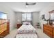 Bright bedroom features a floral comforter, ceiling fan and hardwood dresser at 2244 Plowridge Rd, Fuquay Varina, NC 27526