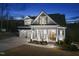 Inviting two-story home boasts a manicured lawn, classic white pillars, and a charming double-door entrance at twilight at 2244 Plowridge Rd, Fuquay Varina, NC 27526