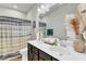 Well-lit bathroom featuring a double sink vanity, decorative pampas grass, and a shower with a curtain at 240 S Stonehaven Way, Clayton, NC 27527