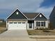 Charming single-Gathering home with a white garage door, stone accents, and gray siding under a cloudy sky at 400 Access Dr, Youngsville, NC 27596