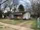 Modest single-story home featuring a covered porch and ramp amidst a spacious, tree-lined yard at 406 S Flanner St, Burlington, NC 27215