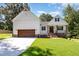 Charming white exterior featuring a two-car garage, brick accents, and a well-manicured lawn under a bright blue sky at 503 Forest Rd, Oxford, NC 27565