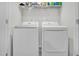 Laundry room with white front-loading LG washer and dryer and storage shelf above at 5813 Empathy Ln, Raleigh, NC 27616