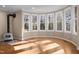 Sunlit living room with wood floors and a fireplace is surrounded by large windows at 6610 Maynard Farm Rd, Chapel Hill, NC 27516