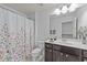 Well-lit bathroom showcasing dark vanity and floral shower curtain, providing a refreshing space at 705 Prince Dr, Holly Springs, NC 27540