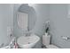 Bright powder room features a pedestal sink with oval mirror, complemented by fresh paint and fixtures at 705 Prince Dr, Holly Springs, NC 27540