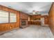 Cozy living room with brick fireplace, wood-paneled walls, and access to the kitchen at 709 S Sellars Mill Rd, Burlington, NC 27217