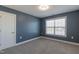 A small, carpeted bedroom with a window and blue walls at 71 Del Corso Ct, Clayton, NC 27527