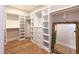 Spacious walk-in closet featuring custom white shelving and storage, and natural wood flooring at 717 Penn Rd, Raleigh, NC 27604