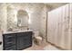 Stylish bathroom with gray and white patterned wallpaper and navy blue vanity with light countertops at 1616 Kirkby Ln, Raleigh, NC 27614