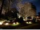 Beautiful home at night with landscaped yard, stone wall accents, and elegant lighting at 1616 Kirkby Ln, Raleigh, NC 27614