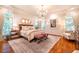 Stunning main bedroom featuring hardwood floors, chandelier, and an abundance of natural light from large windows at 1616 Kirkby Ln, Raleigh, NC 27614