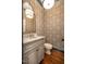 Stylish powder room with patterned wallpaper, marble countertop, and wood flooring offers a touch of elegance at 1616 Kirkby Ln, Raleigh, NC 27614
