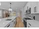 Modern kitchen featuring stainless appliances, white cabinets, quartz countertops, and open layout to living space at 163 Nashua Dr, Louisburg, NC 27549