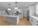 Modern kitchen with white cabinets, stainless steel appliances, large island, and hardwood floors at 163 Nashua Dr, Louisburg, NC 27549