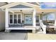 Inviting covered front porch with seating and a hanging porch swing, leads to a charming light blue double-door entrance at 288 Joseph Alexander Dr, Fuquay Varina, NC 27526