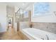 Bright bathroom featuring a bathtub with beige tile surround and a glass-enclosed shower at 301 Kinsale Dr, Chapel Hill, NC 27517
