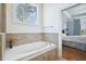 A bathroom featuring a bathtub with beige tile surround and a bedroom in the background at 301 Kinsale Dr, Chapel Hill, NC 27517