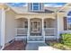 Inviting front porch with white railings and columns, leading to a glass-paneled front door and sidelight windows at 34 Triton Ct, Clayton, NC 27520