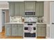 Close-up of kitchen with green cabinets, granite counters, stainless microwave, and a white oven at 34 Triton Ct, Clayton, NC 27520