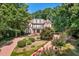 Beautiful brick home featuring a landscaped front yard with flowering bushes and a circular driveway, nestled among lush trees at 405 Silver Creek Trl, Chapel Hill, NC 27514