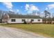 Exterior view of a one-story home with a gravel driveway and lush green lawn at 4194 Abattoir Rd, Angier, NC 27501