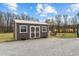 Shed with double doors, a metal roof, and a gravel area surrounded by grass and trees at 4194 Abattoir Rd, Angier, NC 27501