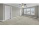 Spacious bedroom featuring neutral walls, carpet, and a ceiling fan with views of the neighborhood at 556 Village Loop Dr, Apex, NC 27502