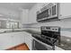 Updated kitchen boasts stainless steel appliances, granite counters, tile backsplash, and modern white cabinets at 556 Village Loop Dr, Apex, NC 27502