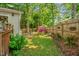 Serene backyard garden with lush greenery, a wooden fence, flowering bushes and outdoor seating at 605 Wyndham Dr, Fuquay Varina, NC 27526