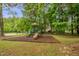 Community playground featuring a green playset, slides, and swings surrounded by lush trees at 605 Wyndham Dr, Fuquay Varina, NC 27526