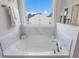 A bathroom featuring a soaking tub with deck-mounted faucet, tile surround, and a window with a view at 800 Emerald Bay Cir, Raleigh, NC 27610