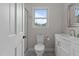Bright bathroom featuring a toilet, a vanity with white cabinets, a sink with chrome hardware, and a glass door shower at 100 Royall Rd, Oxford, NC 27565